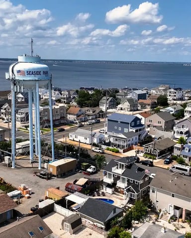 Aerial view of coastal town with water tower, residential homes, and bay in background