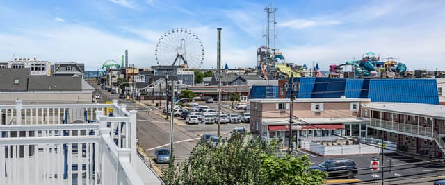 Boardwalk amusement park with Ferris wheel, roller coaster, and water park rides under blue sky